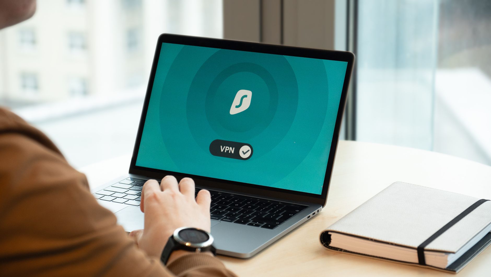 Freelancer przy biurku korzysta z aplikacji VPN na laptopie w biurze