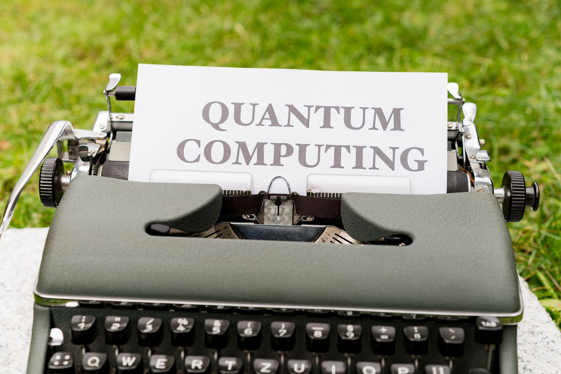 Maszyna do pisania z napisem Quantum Computing stojąca na trawie
