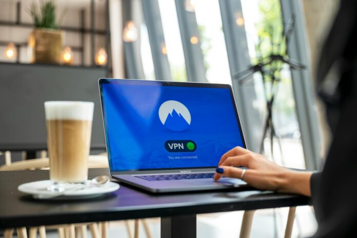 Osoba pracująca zdalnie w kawiarni na laptopie z włączonym VPN Osoba pracująca zdalnie w kawiarni na laptopie z włączonym VPN
