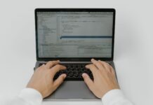 Zbliżenie na dłonie programisty piszącego kod AI na laptopie