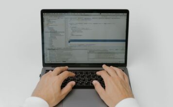 Zbliżenie na dłonie programisty piszącego kod AI na laptopie