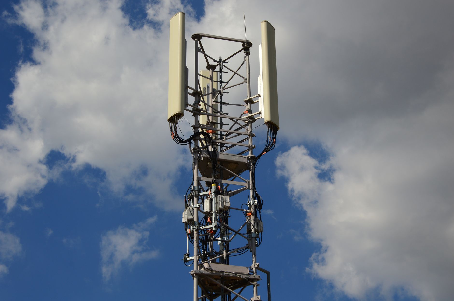Maszt sieci komórkowej 5G z antenami na tle niebieskiego nieba