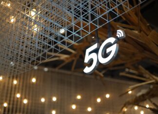 Bezpieczeństwo sieci 5G w praktyce: potencjalne wektory ataków i dobre praktyki dla adminów Podświetlony znak 5G na tle nowoczesnego sufitu w ciepłym oświetleniu
