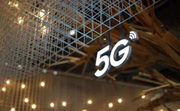 Bezpieczeństwo sieci 5G w praktyce: potencjalne wektory ataków i dobre praktyki dla adminów Podświetlony znak 5G na tle nowoczesnego sufitu w ciepłym oświetleniu