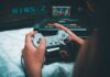 Legalność emulatorów, ROM‑ów i retro‑gier: co wolno miłośnikowi starych konsol Dłonie trzymające retro kontroler Sony z konsolą Sega Mega Drive w tle