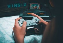 Legalność emulatorów, ROM‑ów i retro‑gier: co wolno miłośnikowi starych konsol Dłonie trzymające retro kontroler Sony z konsolą Sega Mega Drive w tle