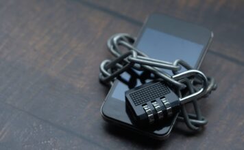 Utrata telefonu bez paniki: szyfrowanie, blokada zdalna i kopie zapasowe w świecie mobilnym Smartfon owinięty łańcuchem z kłódką symbolizującą silne zabezpieczenia